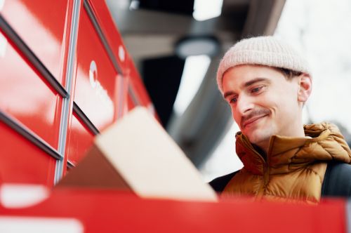 Ung mann med pakke ved en pakkeboks