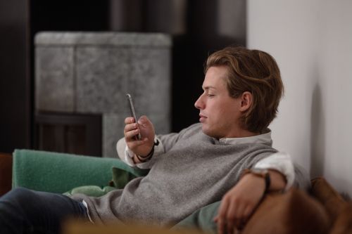 Mann med mobil sitter i en sofa.