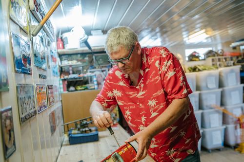 Mann reparerer en gammel lekebil i verkstedet sitt.