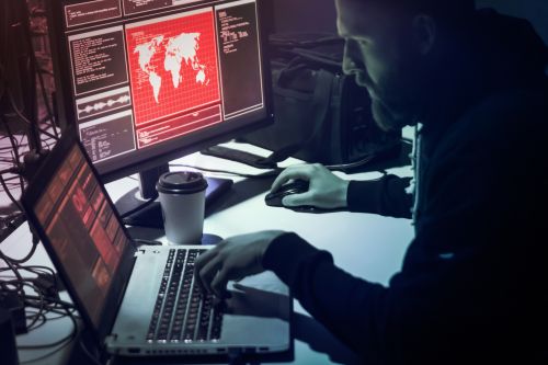 Mann foran datamaskiner i et mørkt rom.