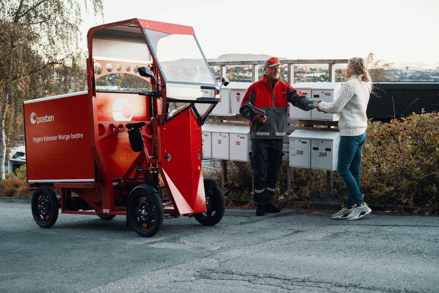 Postbud med Paxster leverer post til kunde foran et postkassestativ