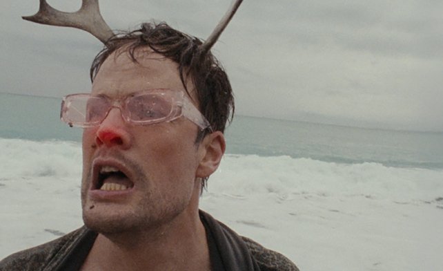 Man with antlers and glasses in the icy wilderness.