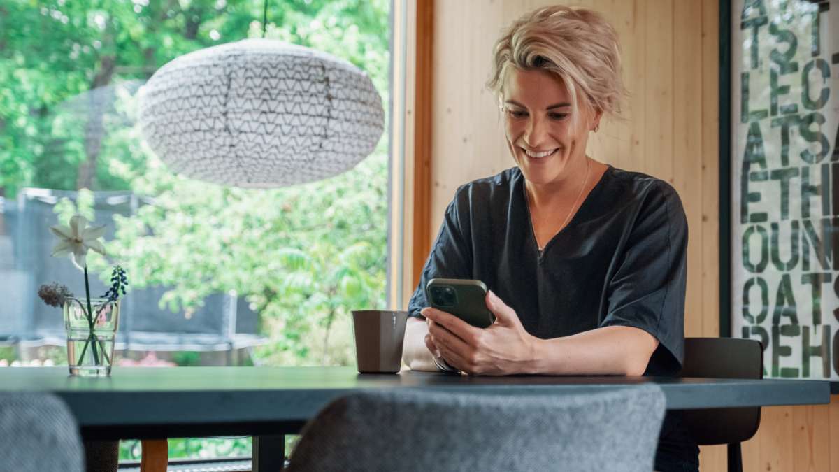 Woman with phone sitting at a table at home.