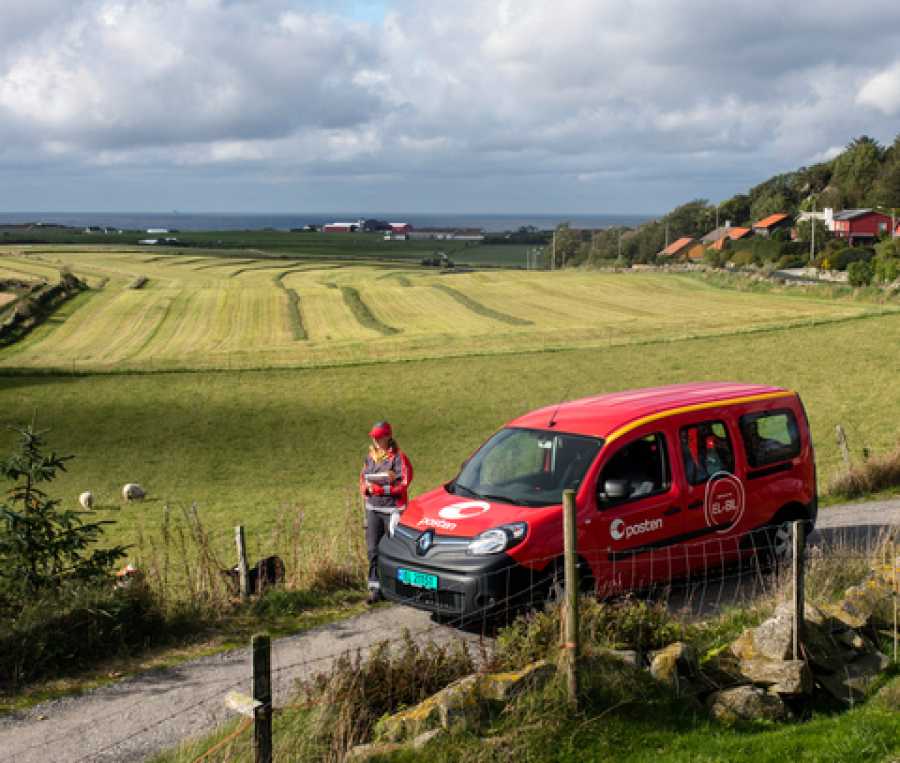 Landpostbud uten bilen sin i et vakkert grønt landskap med jorder og høy himmel.