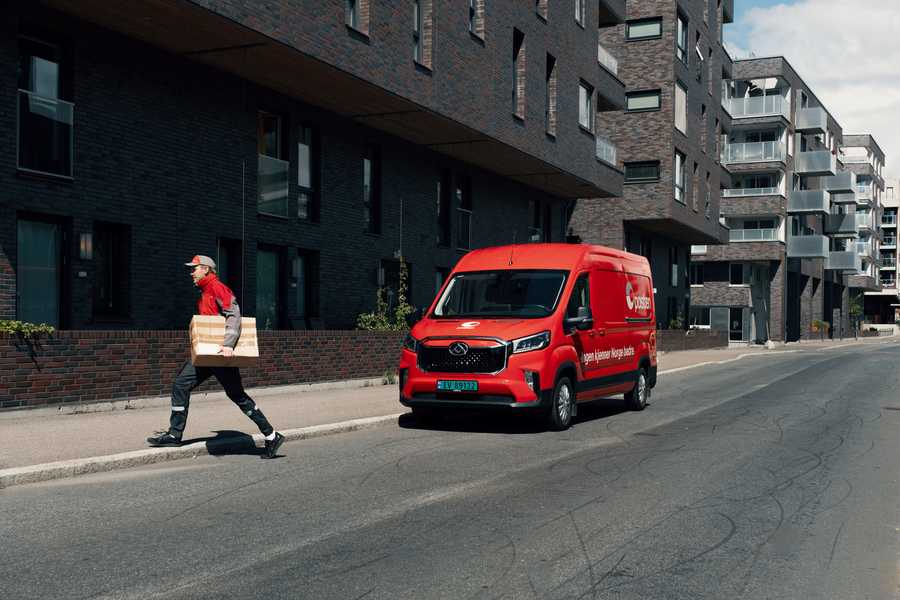 Postbud med pakke og budbil i urbane strøk