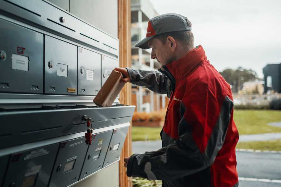 Postbud henter eller leverer en pakke fra en postkasse